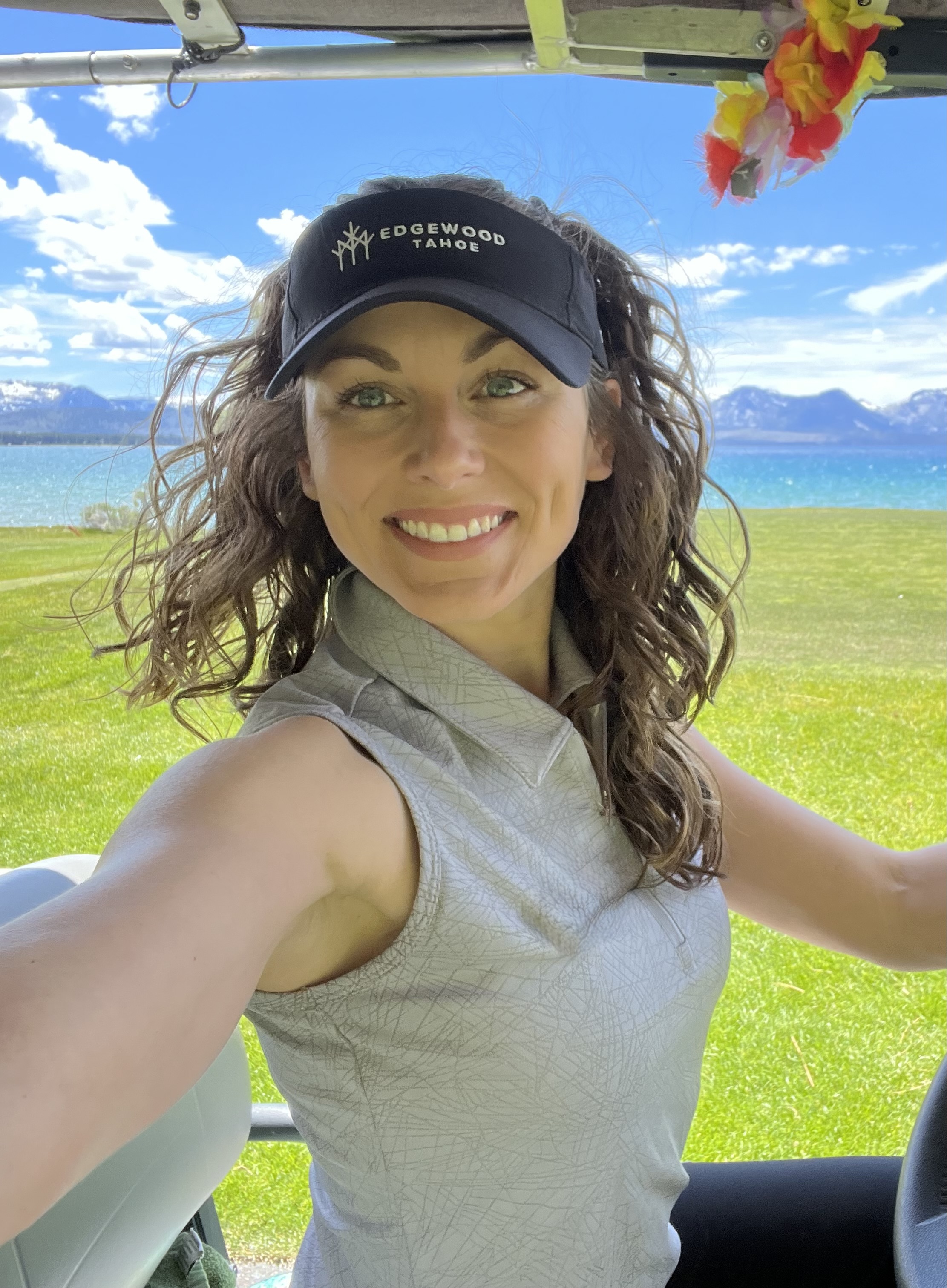 Caitlyn Hathcock in an Edgewood Tahoe visor on the golf course by Lake Tahoe