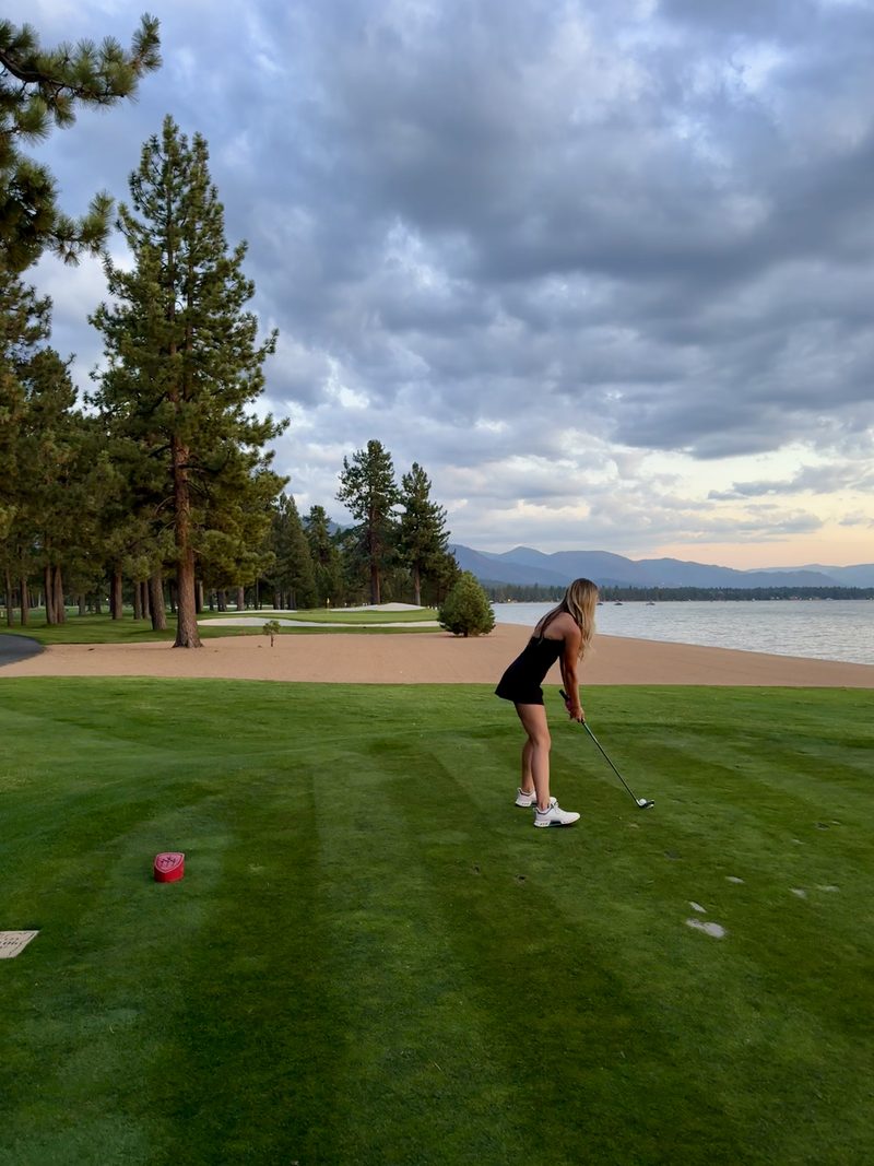 Player teeing off at sunset by the lake
