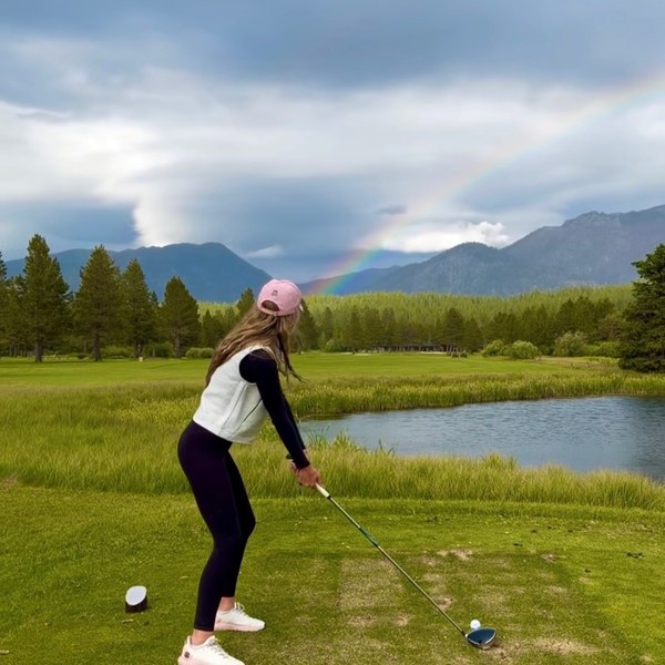 Member teeing off with a rainbow over the Sierra mountains