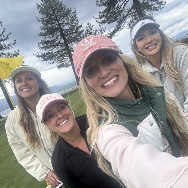 Four members posing for a selfie on the green at Lake Tahoe