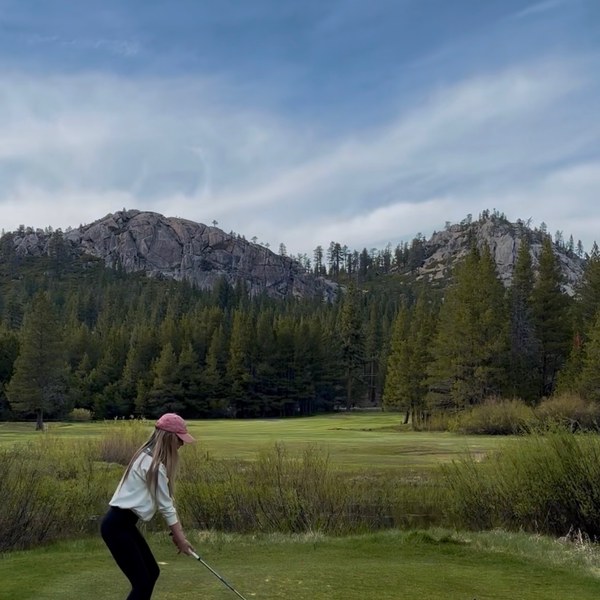 Member teeing off below granite Sierra peaks